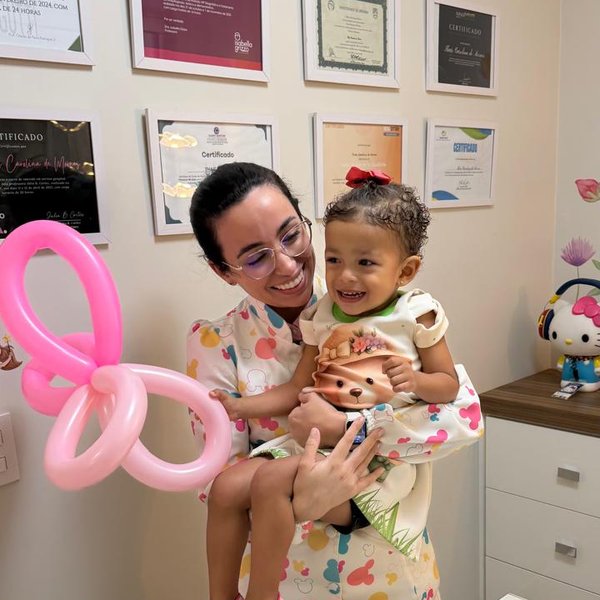 Dra. Thaís Moraes com uma pequena paciente no colo